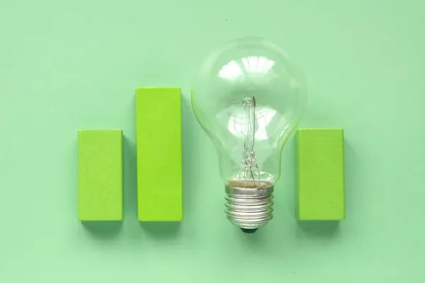 Image of a green bar chart, with one bar being an LED light bulb. 