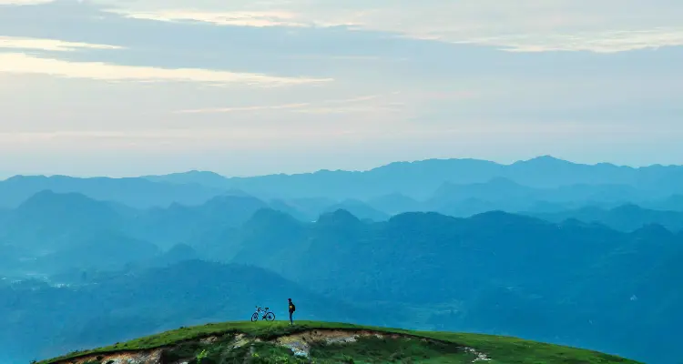 Image of a sustainable travel destination, showing a cyclist with terrain in the distance